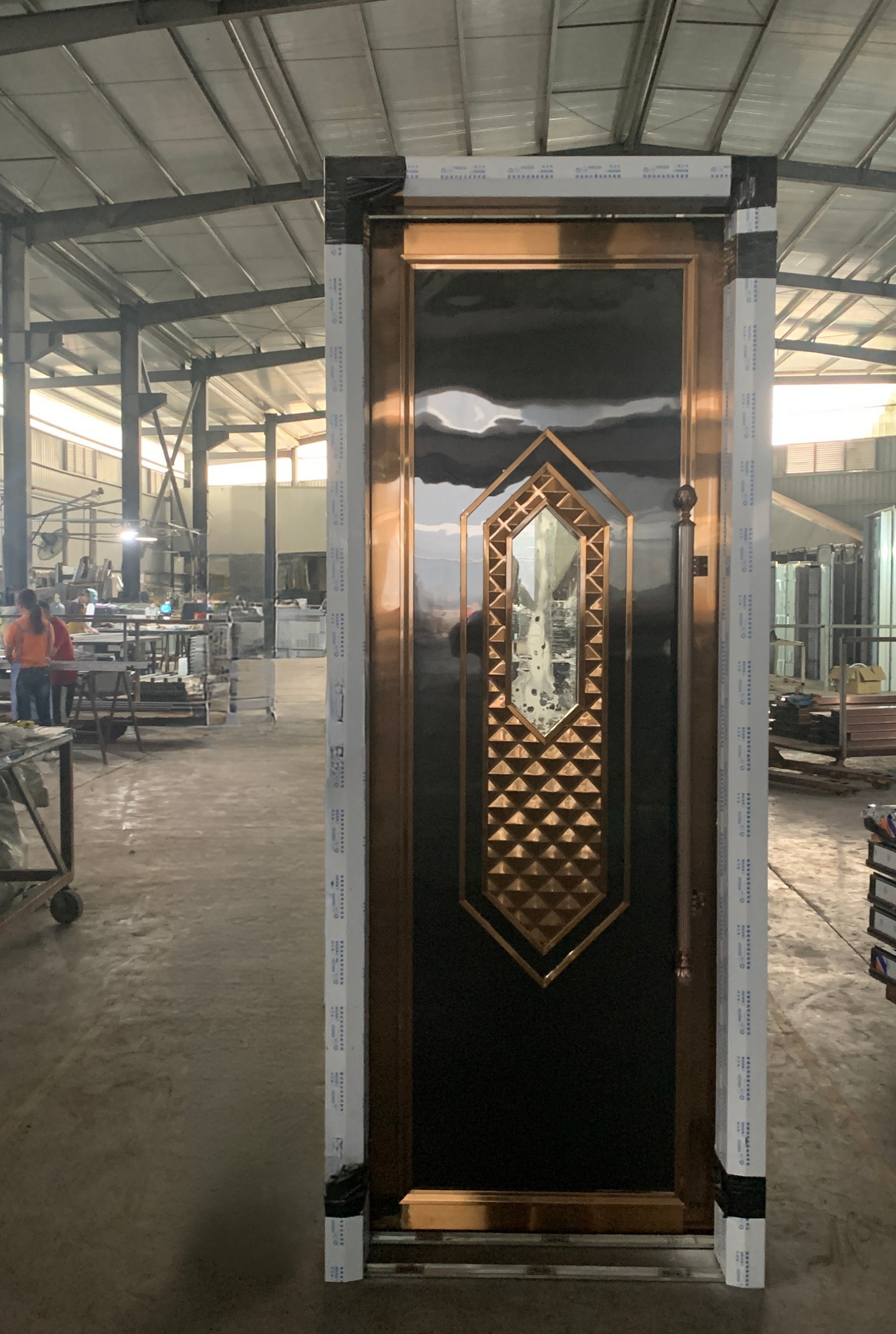 Black soundproof door with geometric diamond-shaped copper inlay and reflective panel, designed for stylish entertainment spaces.