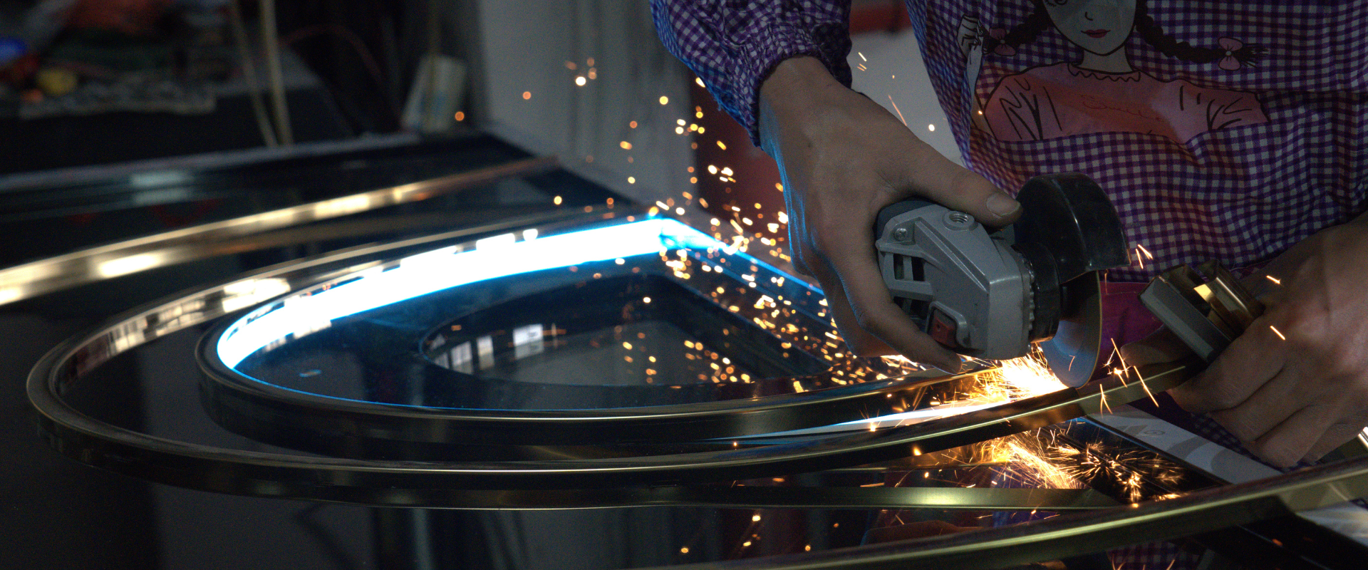 Close-up of a worker using a grinder to process a soundproof door frame with sparks flying, showcasing the high-quality craftsmanship in the manufacturing process