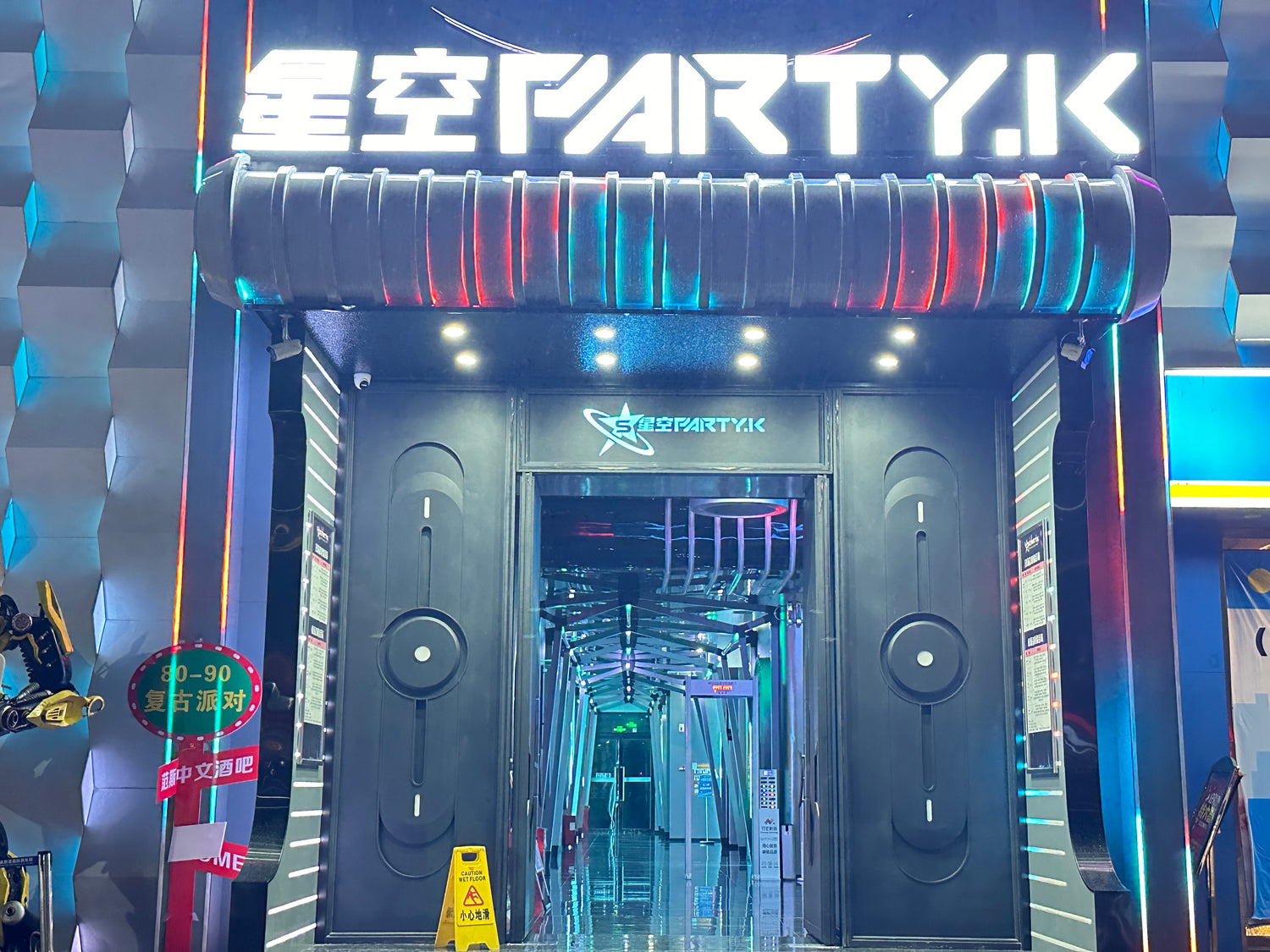 Entrance of a KTV venue featuring illuminated branding and a soundproof door, showcasing the use of high-quality soundproofing for a vibrant entertainment space