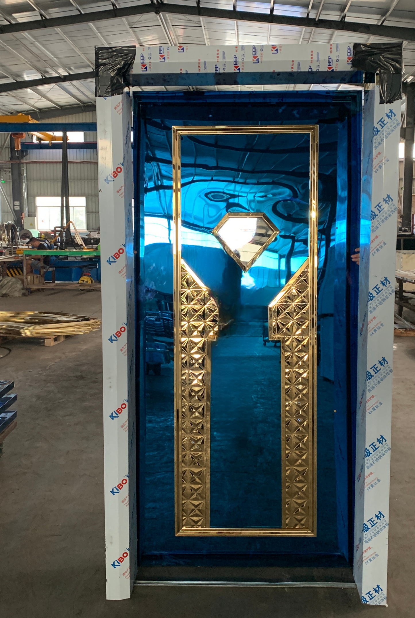 Blue stainless steel soundproof door with intricate gold inlaid diamond-shaped panel in the center, designed for upscale interiors like KTV rooms and luxury venues.