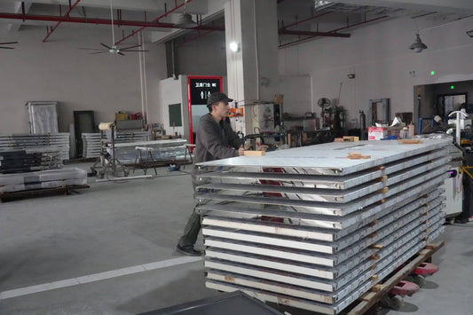 Factory worker preparing stacked custom soundproof doors for large project shipment, showcasing mass production capability