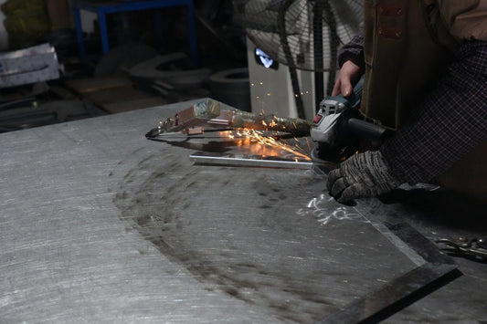 Factory worker grinding door hardware components, highlighting the precision craftsmanship behind acoustic performance